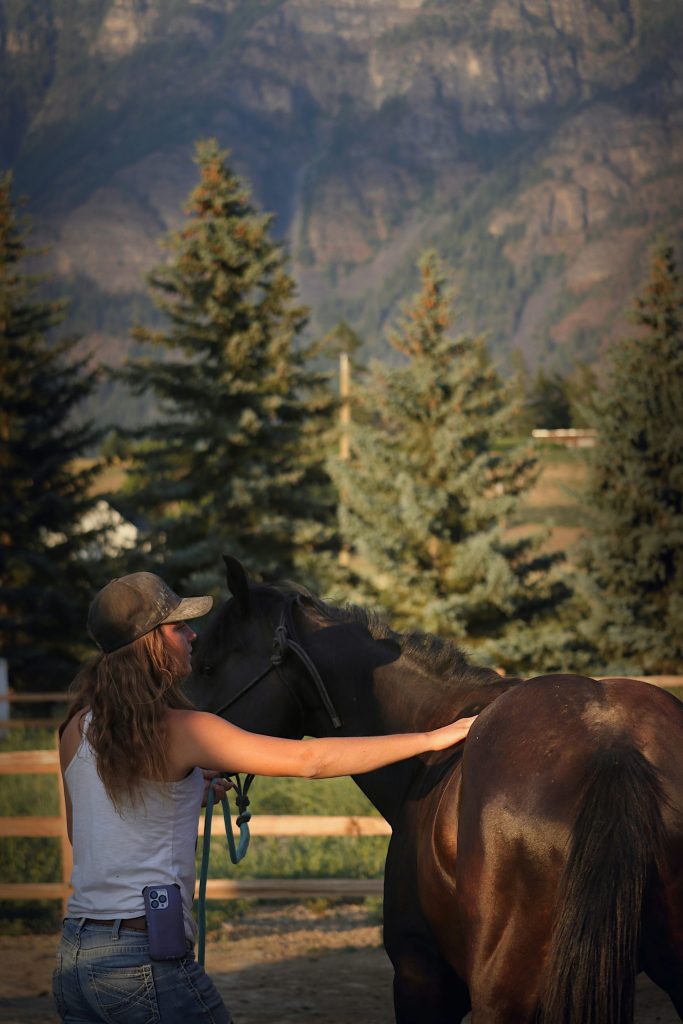 Eine Frau steht neben einem braunen Pferd